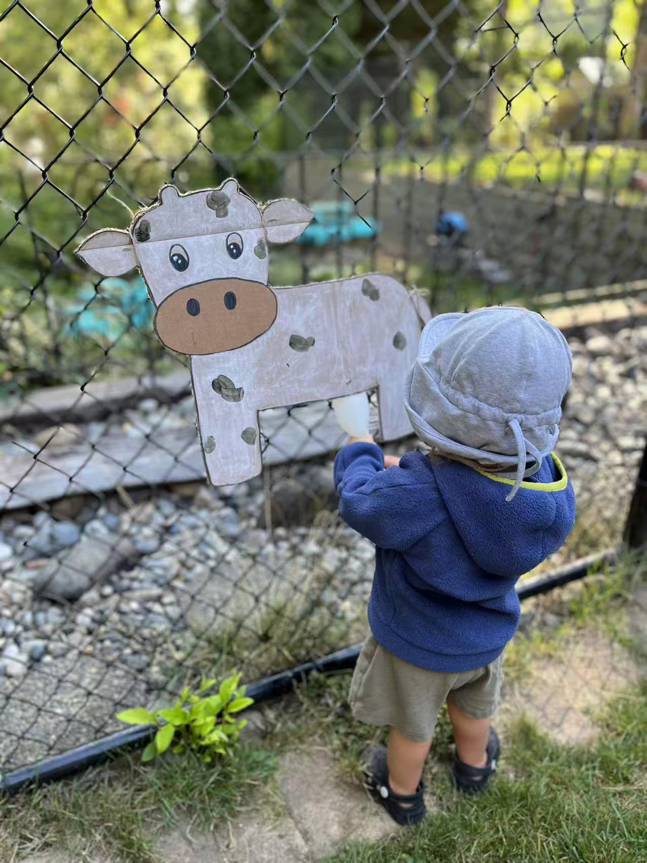 Child exploring a handmade farm animal craft in the outdoor play area at Forest Cubs Childcare
